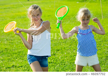 Two small sisters playing in badminton Two small sisters playing in badminton 46097702