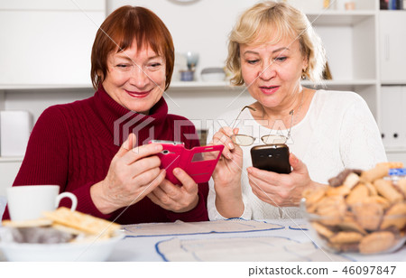 Two positive senior women using phones 46097847