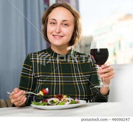 Woman eating salad and drinking wine 46098247