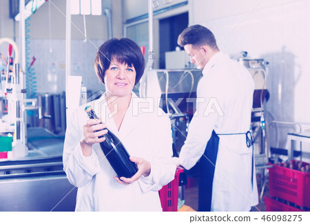 Woman worker displaying wine bottle 46098275