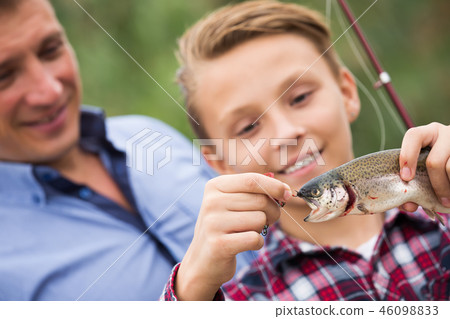 Smiling teenage boy catching on hook fish Smiling teenage boy catching on hook fish 46098833