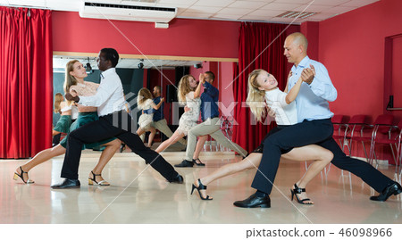 Adult pairs dancing tango movements in modern dance studio 46098966