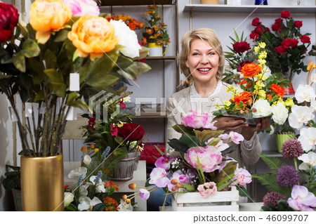Adult smiling female customer choosing flowers Adult smiling female customer choosing flowers 46099707