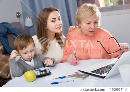 Woman is talking her mother how to fill utility bills with laptop Woman is talking her mother how to fill utility bills with laptop 46099744