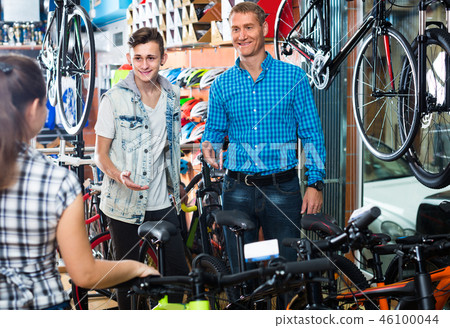 father with son and female seller in bike store. 46100044