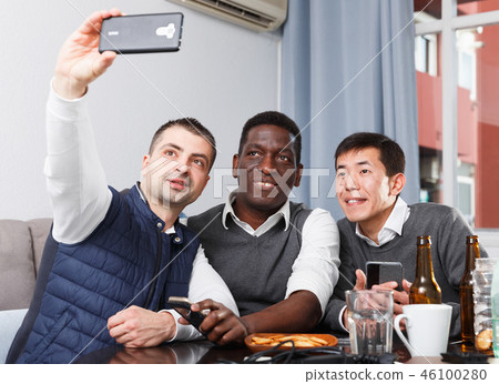 Smiling men are resting and taking selfie by smartphone together Smiling men are resting and taking selfie by smartphone together 46100280