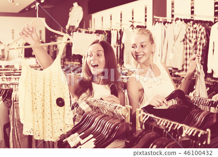 two girls buying tops in clothes store . 46100432
