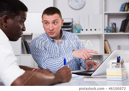 Concentrated businessman talking to colleague in office Concentrated businessman talking to colleague in office 46100872