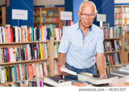 bespectacled senior male customer visiting bookshop in search of interesting fiction 46101307