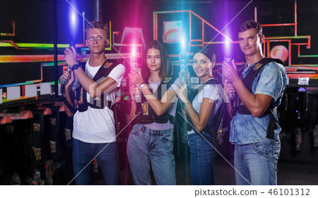Portrait of positive young friends standing with laser guns duri Portrait of positive young friends standing with laser guns duri 46101312