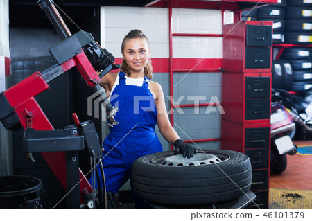 Happy woman technician standing with wheel Happy woman technician standing with wheel 46101379