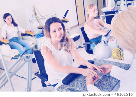 Two women clients having manicure done in nail salon Two women clients having manicure done in nail salon 46101516