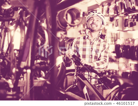 Man in helmet chooses convenient bike Man in helmet chooses convenient bike 46101517