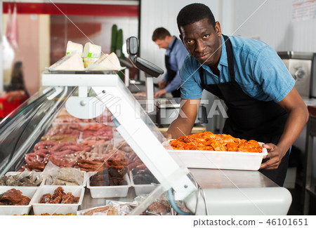 Skillful butcher with colleague working behind counter Skillful butcher with colleague working behind counter 46101651