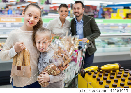 Family is standing with cart with products in the supermarket. Family is standing with cart with products in the supermarket. 46101655