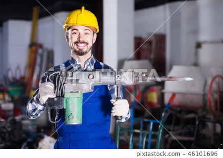 working man practicing his skills with pneumatic drill at workshop 46101696