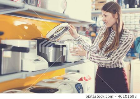 Young positive female housewife choosing multicooker Young positive female housewife choosing multicooker 46101698