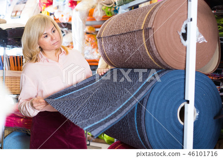 Mature woman customer choosing colored carpeting Mature woman customer choosing colored carpeting 46101716