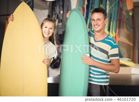 couple is demonstraiting surfboard in nautical shop. 46101720