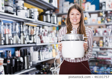 Polite saleswoman showing slow cooker in store Polite saleswoman showing slow cooker in store 46101757
