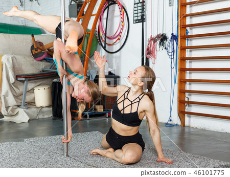 Woman exercising pole dance with trainer Woman exercising pole dance with trainer 46101775