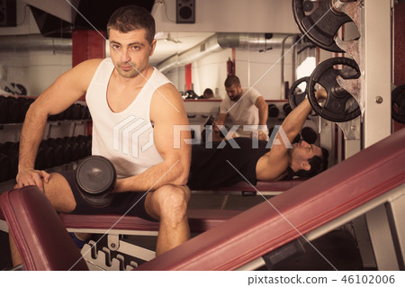 Guy during workout in gym with dumbbells Guy during workout in gym with dumbbells 46102006