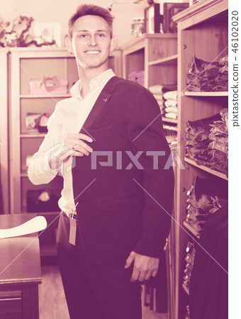Smiling male choosing new suit in male store 46102020