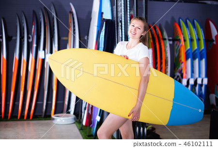 Woman is posing with surfboard in store on the beach. 46102111