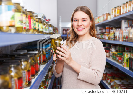 Positive woman customer holding pickle goods in food store Positive woman customer holding pickle goods in food store 46102311