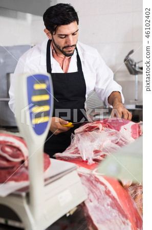 Man butcher is cutting meat on his workplace in the market. Man butcher is cutting meat on his workplace in the market. 46102402
