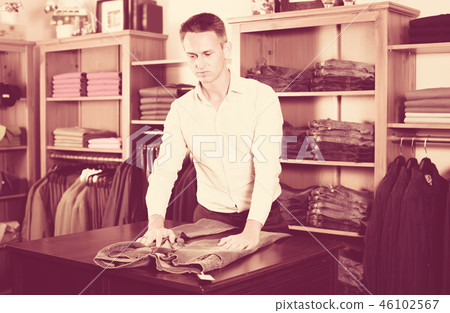 Young guy deciding on new trousers Young guy deciding on new trousers 46102567