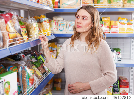 Positive woman buyer choosing groats in grocery food store 46102810