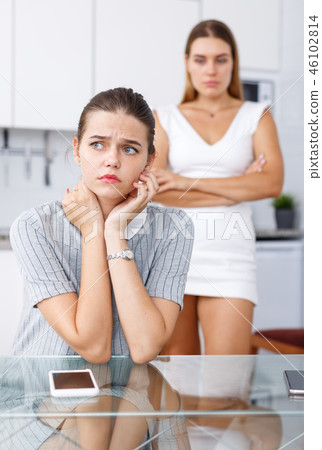Sad girl sitting at table after conflict, woman friend on backround 46102814