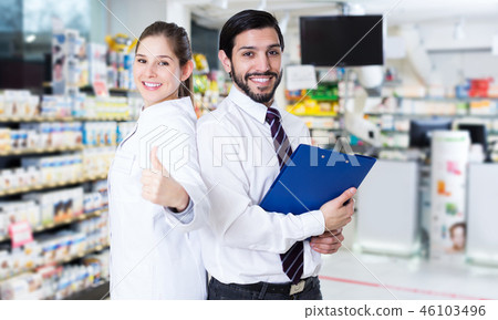 pharmacist and expert standing near shelves with medicines pharmacist and expert standing near shelves with medicines 46103496
