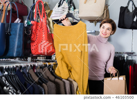 Smiling woman choosing turtleneck sweater Smiling woman choosing turtleneck sweater 46103500