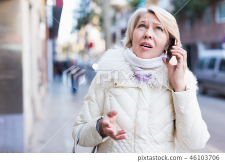 Female in the city in scarf and jacket talking on phone 46103706