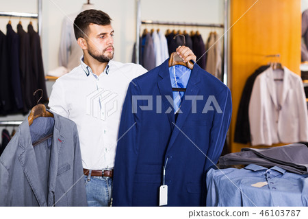 Smiling male assistant showing various jacket Smiling male assistant showing various jacket 46103787