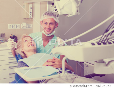 Male dentist treating female patient 46104068