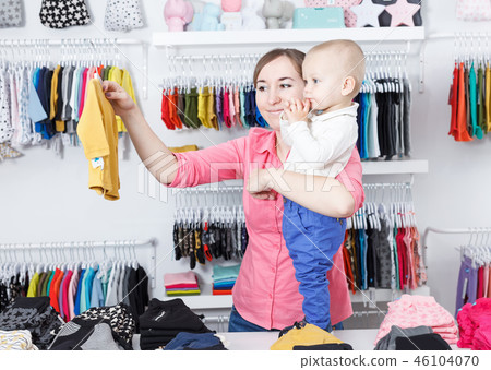 Positive woman with her kid are choosing clothes in store Positive woman with her kid are choosing clothes in store 46104070