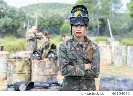 Female paintball player in camouflage and black mask with traces of paint Female paintball player in camouflage and black mask with traces of paint 46104071