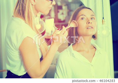 female makeup artist applying cosmetics for woman female makeup artist applying cosmetics for woman 46104283