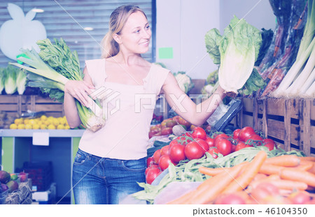 happy young female customer holding fresh celery and leek happy young female customer holding fresh celery and leek 46104350