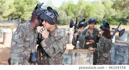 Male paintball team discussing tactic of game with opposing team Male paintball team discussing tactic of game with opposing team 46104356