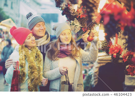 joyous family couple with teen girl choosing Christmas decoration 46104423