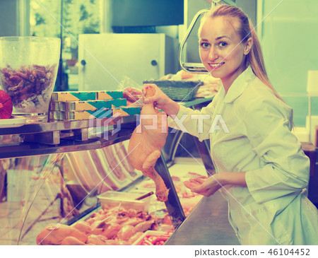 Young woman seller holding fresh whole chicken Young woman seller holding fresh whole chicken 46104452