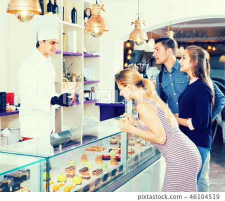 Man is offering delicious cakes from showcase Man is offering delicious cakes from showcase 46104519