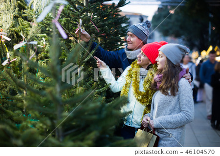 Mom, dad and daughter buying New Year tree 46104570