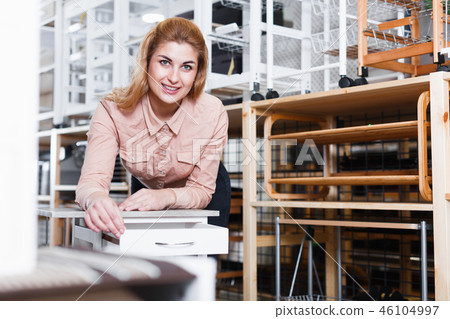 Woman looking for kitchen trolley in furniture salon Woman looking for kitchen trolley in furniture salon 46104997
