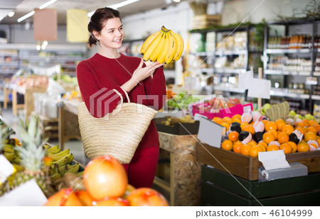 Portrait of brunette girl buying ripe bananas in supermarket Portrait of brunette girl buying ripe bananas in supermarket 46104999