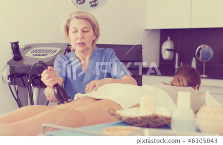 Beautician performing machine cosmetological procedure 46105043